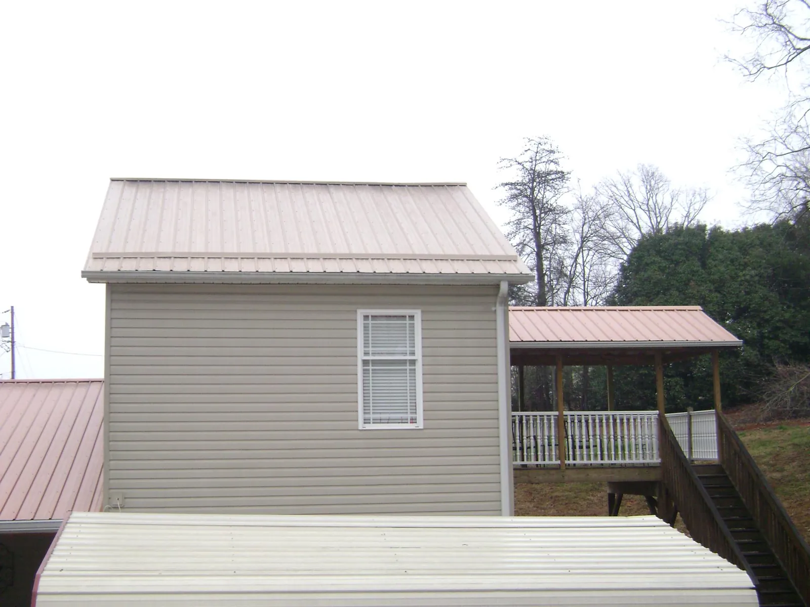 Tan metal roofs on a two story addition and attached porch, from a Roof Replacement job in Woodstock
